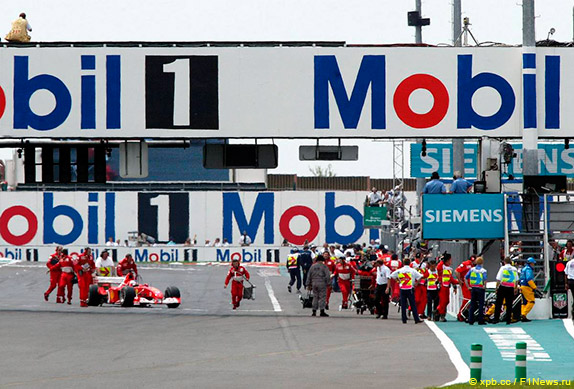 Машину Баррикелло откатывают на пит-лейн после старта прогревочного круга на Гран При Франции 2002 года