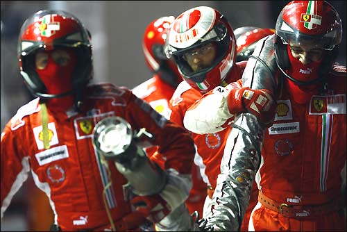 Механики Ferrari возвращают в боксы заправочный шланг, вырванный Фелипе Массой...
