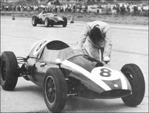 Тони Брукс проносится мимо толкающего машину Джека Брэбэма на финише Гран При США 1959 года