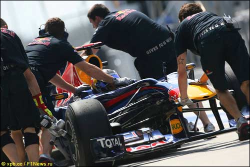 Механики Red Bull Racing закатывают в боксы машину Себастьяна Феттеля