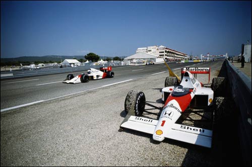 Победитель Гран При Франции 1989 года Ален Прост проезжает мимо отказавшей машины своего напарника Айртона Сенны