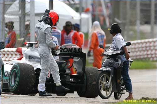 Михаэль Шумахер изучает свой Mercedes после быстрого схода